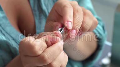 女人用指甲镊割角质层近距离。美甲和指甲护理概念。做家庭美甲的女人。