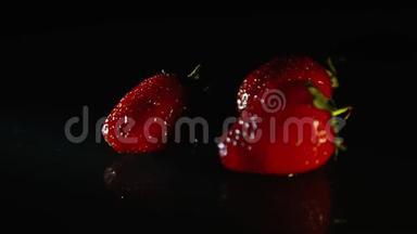 三颗草莓在一缕阳光下美丽地躺在一张黑色的桌子上。高清