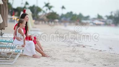 一家人的妈妈和孩子享受白色海滩上的海景。 一家人放松地坐在日光浴床上看着美丽