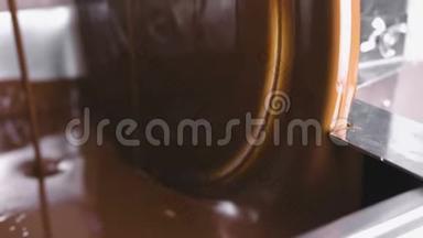 巧克力回火机中的温液巧克力.. 特写镜头。 巧克力糖果的生产。