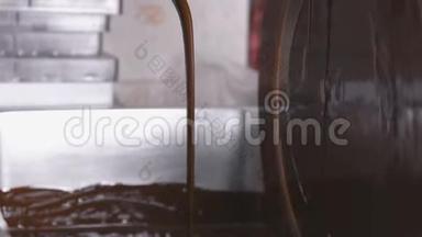 巧克力<strong>回火</strong>机中的温液巧克力.. 特写镜头。 巧克力糖果的生产。