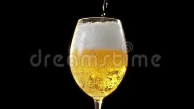 金色泡沫啤酒慢慢倒入玻璃杯，黑色背景下的啤酒杯，啤酒中的气泡，淡啤酒