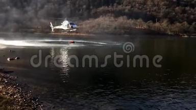 消防直升机在意大利瓦尔甘纳的盖尔拉湖上方的一场山火中取水