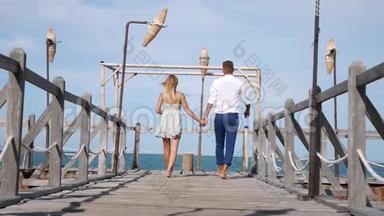 年轻的幸福夫妇在蓝天背景上的木墩上行走。 浪漫的概念。 高清，1920x1080。