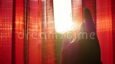 女孩打开红色的窗帘，用手在阳光`的光<strong>线下</strong>玩耍。 手工特写
