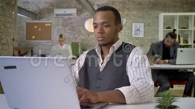 年轻的非洲女商人正在办公室里用笔记本电脑打字，同事正在与技术、工作理念<strong>建立</strong>联系