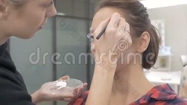一位专业的化妆师在模特的脸上画身体艺术.. 为选美比赛做准备。