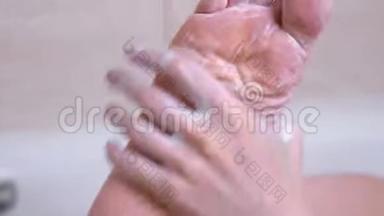 女人正在浴室里用手洗脚。 把磨砂放在脚上。