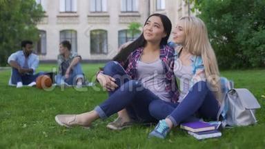 最好的朋友坐在大学附近的草坪上聊天，支持和友谊