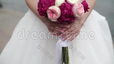 新娘捧着一束白色、粉红色和红色的玫瑰。 摇摆的丝带。 户外活动缓慢