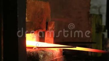 在锻造厂用金属制造剑。 铁匠`手从炉子里抽出铁水毛坯.
