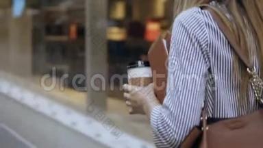 年轻时尚的女商人拿着文件和咖啡杯在街<strong>上走来走去</strong>，用智能手机聊天。