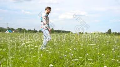 一个穿破牛仔裤的帅哥独自在草地上走来走去。