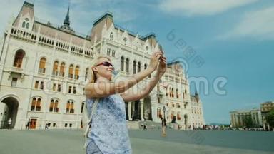 一位女游客在匈牙利议会背景下拍摄自己的照片。 欧洲旅游业