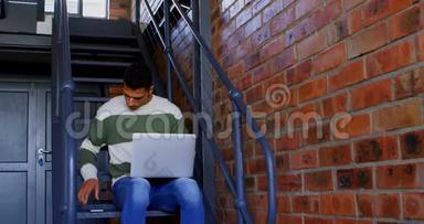 男子在4k楼梯上使用笔记本电脑时使用移动电话