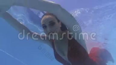 化妆的年轻女子在水下游泳，穿着红色连衣裙，4k