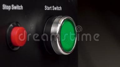 框架中的两个按钮。 绿色启动开关和红色停止开关按钮。 手指按绿色启动开关按钮。