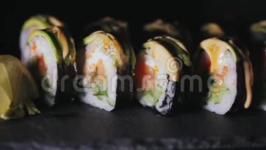 寿司配<strong>三文鱼</strong>片和<strong>新鲜</strong>黄瓜。 在黑石板上吃寿司。 特写