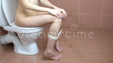 年轻女子<strong>坐</strong>在浴室的马桶上，手里拿着卫生纸。 <strong>厕</strong>所的使用
