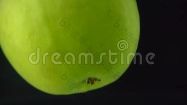 绿色的苹果在黑色背景下缓慢地落入水中