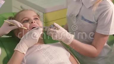 美丽开朗的女孩对待儿童牙医的牙齿。 她绿色地坐在牙科椅上，微笑着。