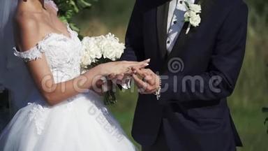 婚礼情侣在夏季的户外仪式上戴上结婚戒指