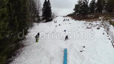 鸟瞰：冬季白天滑雪板沿着斜坡行驶。 冬天，滑雪者在滑雪场的山坡上尽情享受