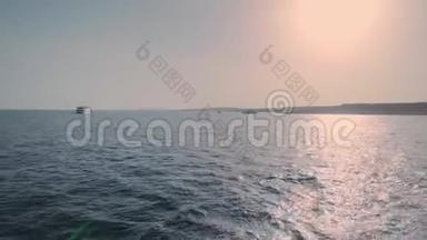 船尾在海洋日落拍摄。 大船后面的水沫痕迹一直延伸到地平线