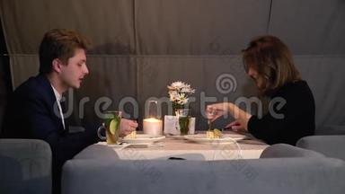 一对情侣在餐馆约会，一个女孩在吃蛋糕，一个穿西装的男人在喝茶，一个滑头在射击