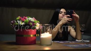 一个女人坐在一家餐馆里，端着一杯酒，用智能手机打印短信，有点慢动作