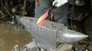 在锻造厂用金属制造刀。 紧紧抓住铁匠`双手在铁锤上敲打铁水