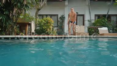 暑假的年轻人在炎热的晴天先跳进<strong>蓝色</strong>的游泳池里喝点东西。 一个人潜入