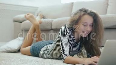 地毯上可爱的少女用笔记本电脑工作。 stadicam拍摄的快乐少女靠近一个有笔记本电脑的沙发。 少女使用