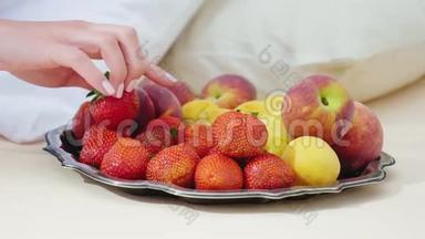 女人`手选择美味的水果。 盘子站在枕头旁边-<strong>床</strong>上的早餐和<strong>浪漫</strong>的<strong>浪漫</strong>