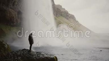 带着动作镜头的年轻人站在冰岛的Gljufrabui<strong>瀑布</strong>附近，<strong>拍摄</strong>水流的视频。