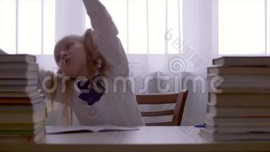 肖像学校女孩玩得很开心，在桌上和课本堆跳舞