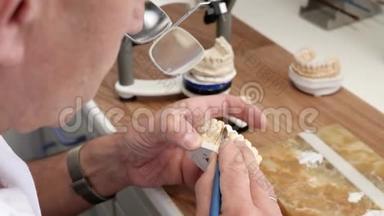 在实验室工作场所，牙科技师在牙齿假体上绘制白色陶瓷釉