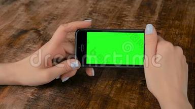 女子手持黑色智能手机与空白绿色屏幕-模拟概念