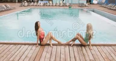 两个女孩在酒店泳池边<strong>摆姿势</strong>。 <strong>年轻女子</strong>穿着一件泳衣坐在游泳池的边缘，<strong>摆姿势</strong>