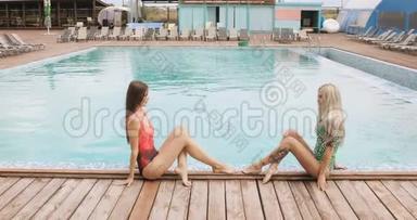 两个女孩在酒店泳池边<strong>摆姿势</strong>。 <strong>年轻女子</strong>穿着一件泳衣坐在游泳池的边缘，<strong>摆姿势</strong>
