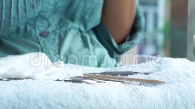 在家中修指甲时拿指甲档案的女人。 手法工具躺在毛巾上.. 家居指甲及指甲护理