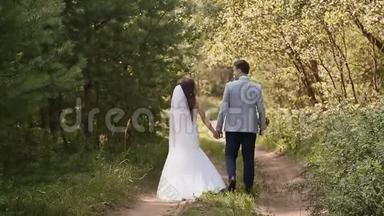 新娘穿着白色礼服，在森林里新郎。 他们牵着手一起走。 一起快乐。 <strong>结婚纪念日</strong>。