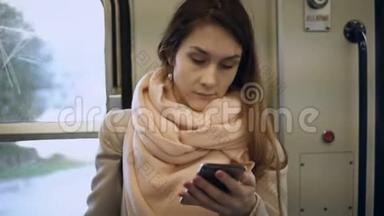 年轻迷人的女人站在地铁里用智能手机。 布鲁内特女士在火车上上网。