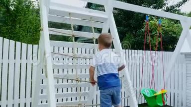 夏天，在花园里，孩子，一个四岁的男孩爬上孩子们`操场上的楼梯。 家庭<strong>开支</strong>