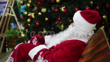 圣诞老人坐在圣诞树旁舒适的摇椅上，充满神奇的气氛