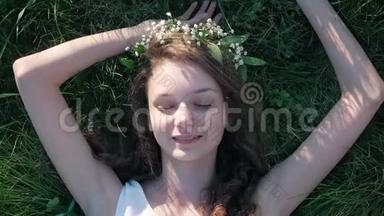 慢<strong>镜头</strong>：一个穿着白色花裙躺在草地上的白人女孩的<strong>俯视镜头</strong>