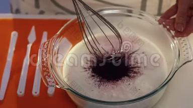 玻璃碗中深紫色和白色物质的手搅拌慢动作