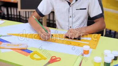 一个男孩坐在桌旁，用铅笔和一把大尺子画画