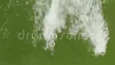 绿色水中的白色气泡流。 泼水溅出并产生湍流气泡..