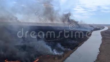 大自然的紧急灾难，大片野火在干燥的田野上快速移动，烟雾在河流附近上升到天空，鸟眼